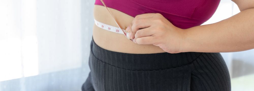 woman measuring waist with measuring tape