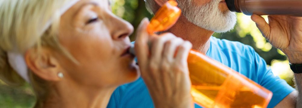 man and woman drinking out of water bottles side by side