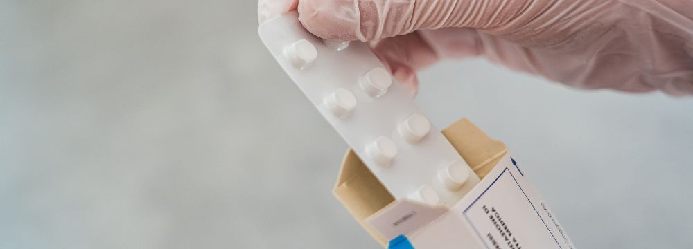 person with glove pulling pill pack out of envelope