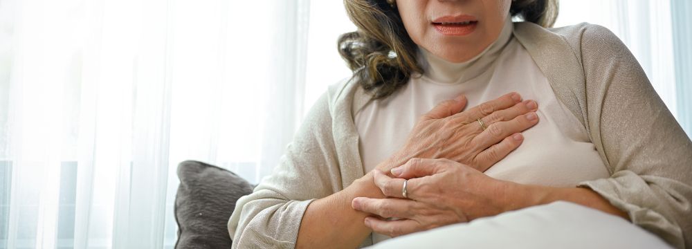 Woman holding chest with hands folded over