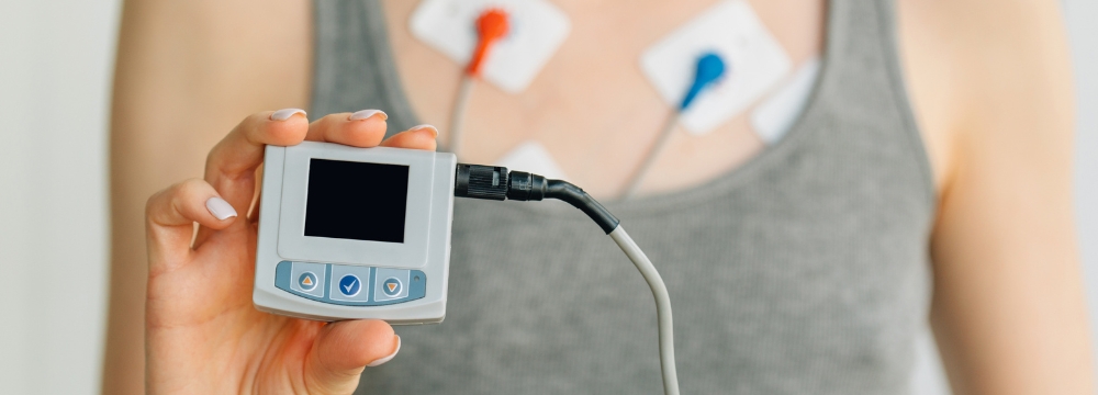 Woman wearing holder monitor to monitor her heart, holding device in hand