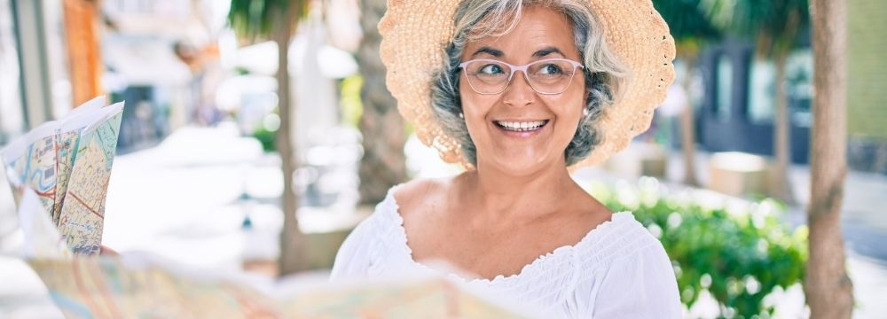  Woman tourist in sun hat, looking at map of city 